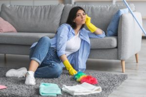 Upset woman tired of cleaning sitting on floor carpet