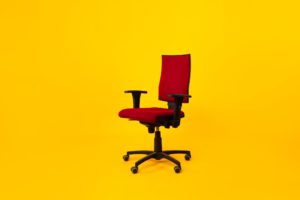 Empty Adjustable Ergonomic Office Chair With Armrests Over Yellow Background